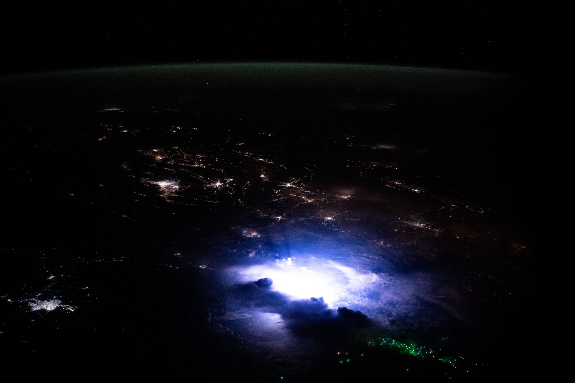 Lightning illuminates clouds above Southeast Asia at night, photographed from the ISS.